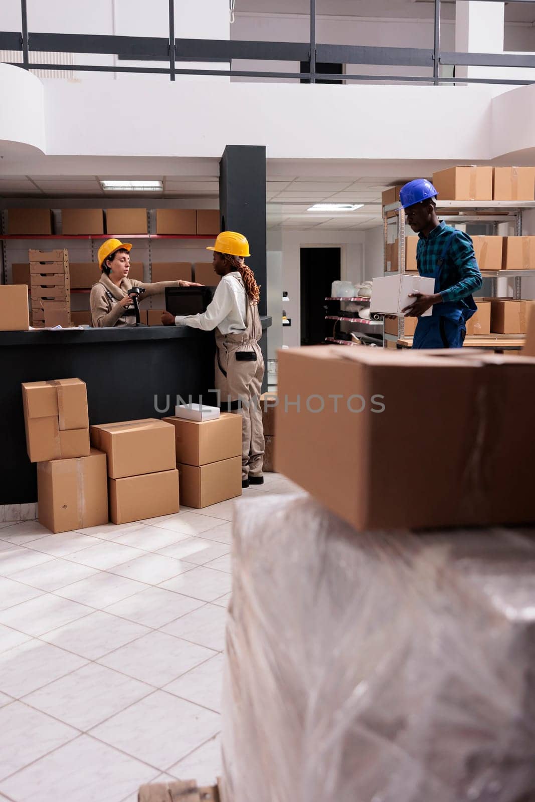 Shipping department operators packing order in cardboard box and checking barcode at registration desk. Diverse man and women delivery managers team working in distribution center warehouse