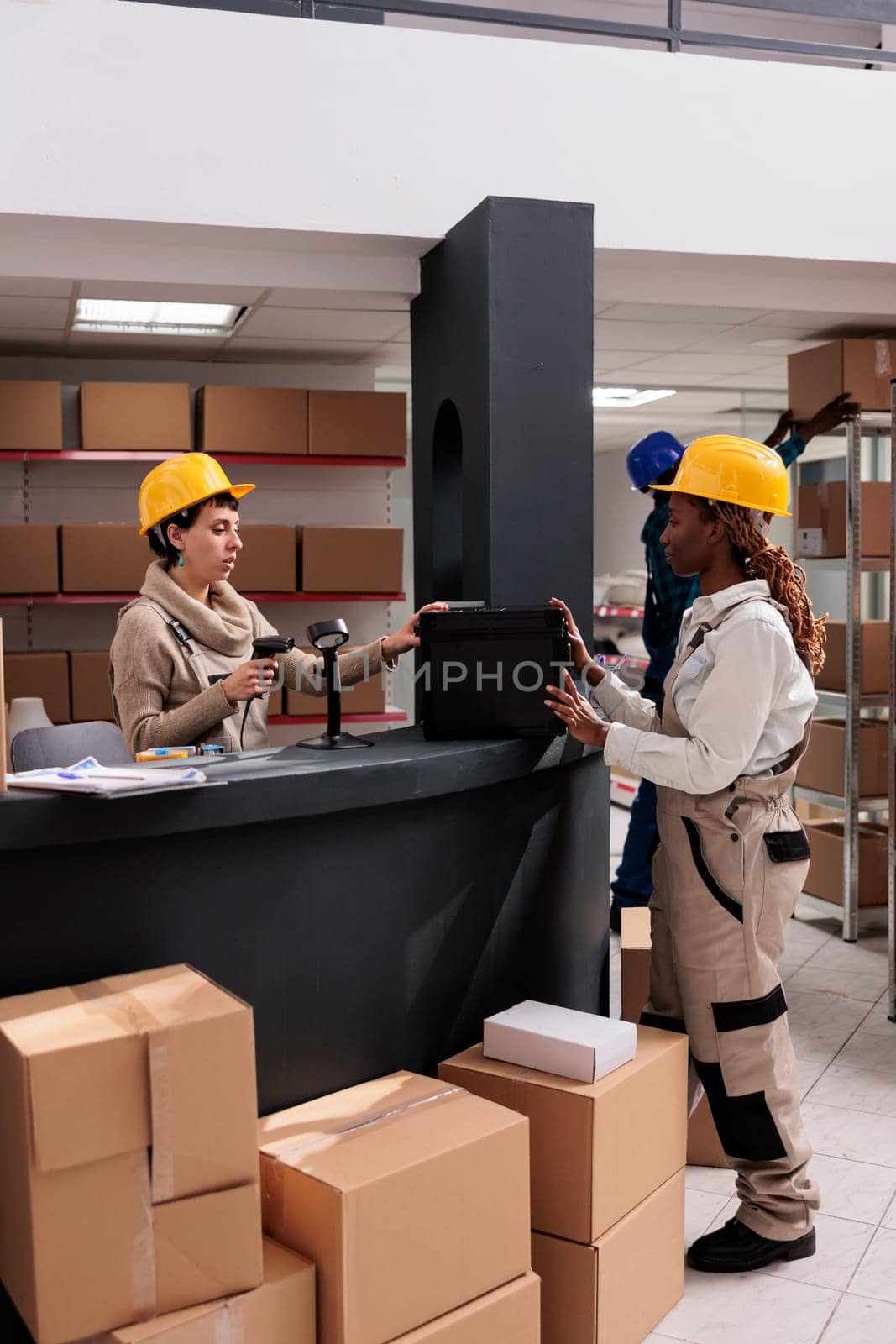 Warehouse manager scanning black case at counter desk and doing inventory. Industrial storehouse coworkers checking stock supply and using barcode scanner at product at delivery office reception