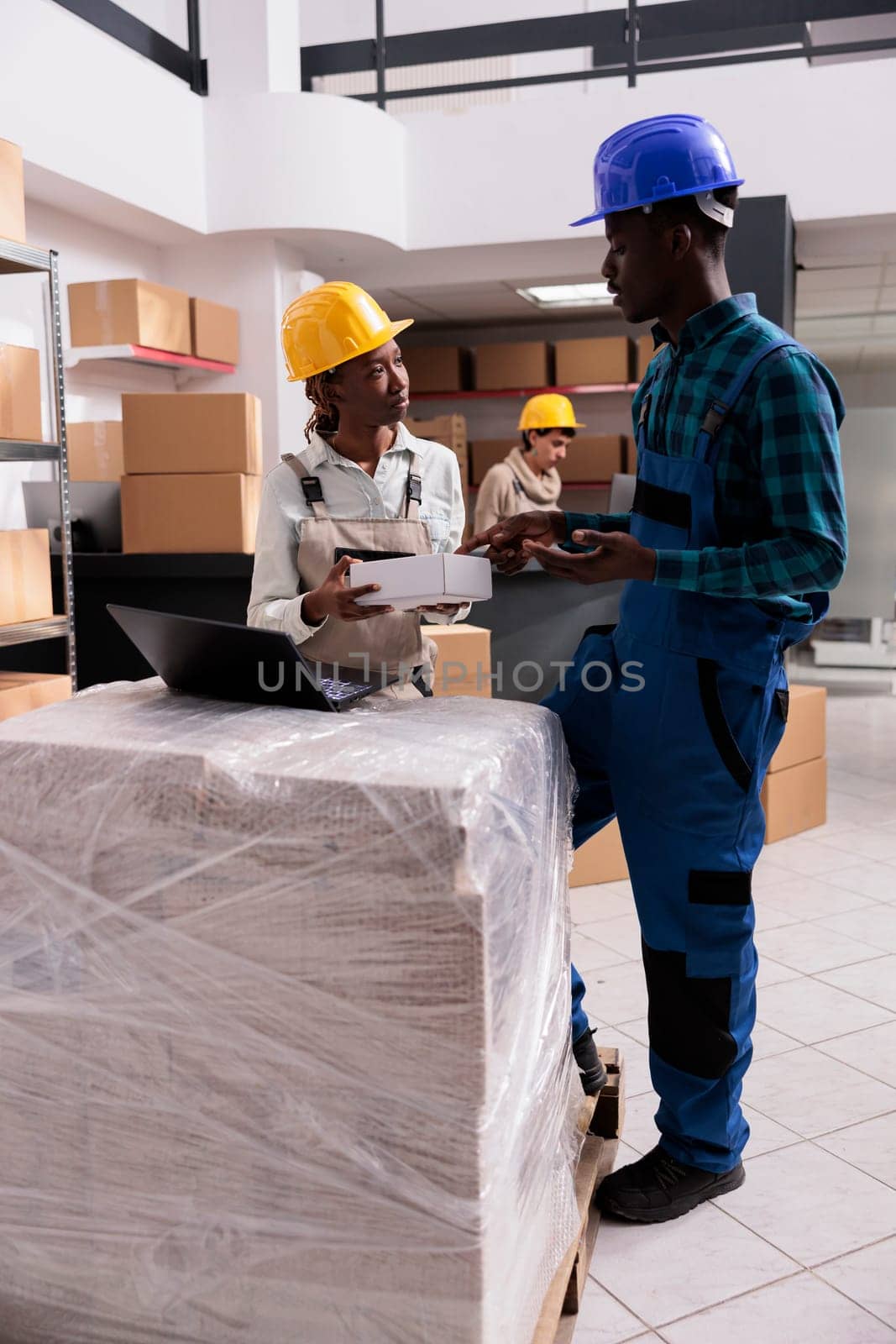 Shipping manager giving box and checking invoice on laptop by DCStudio