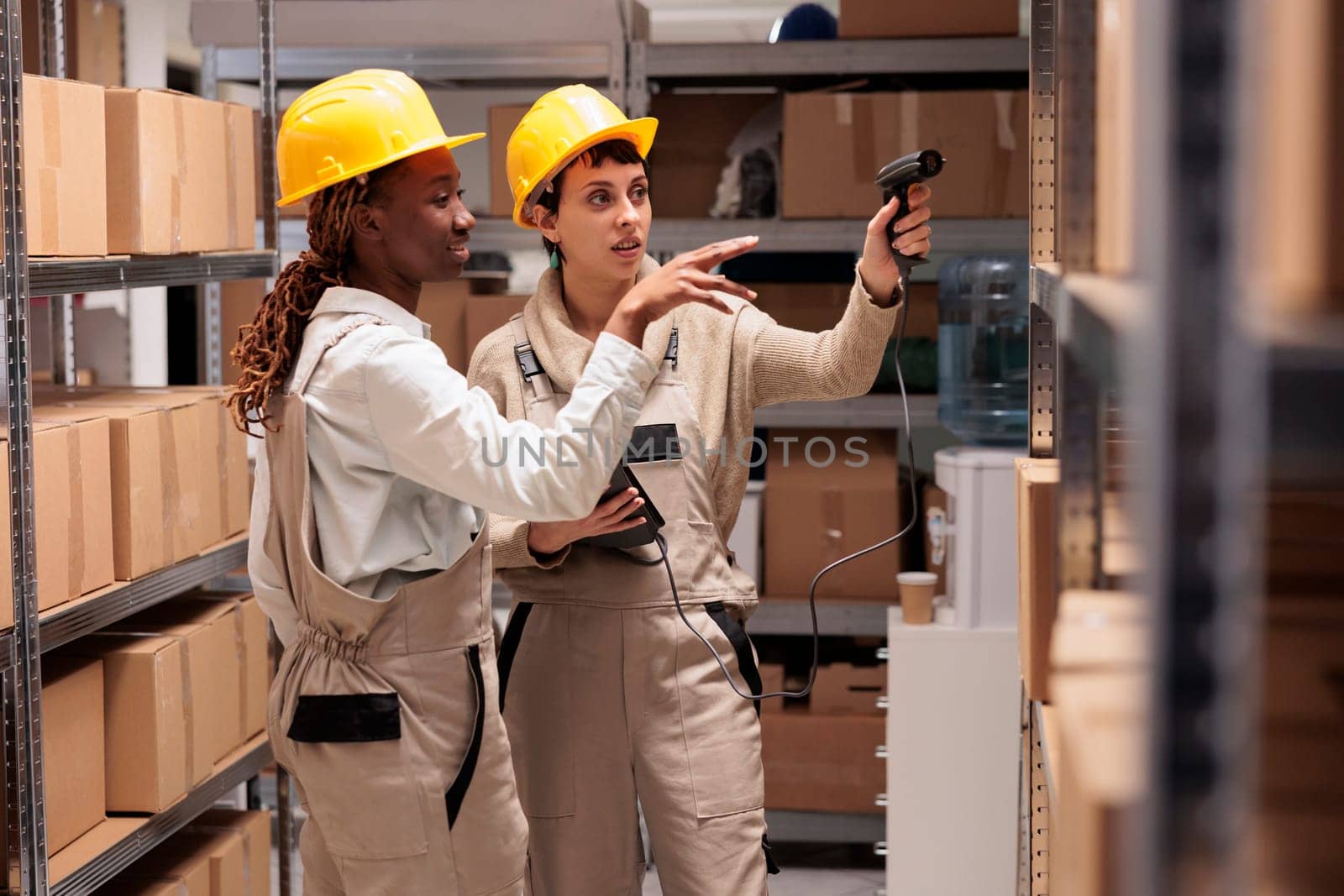 African american and caucasian warehouse operators scanning cardboard boxes barcodes and discussing parcels tracking. Storehouse coworkers preparing customer order for delivery