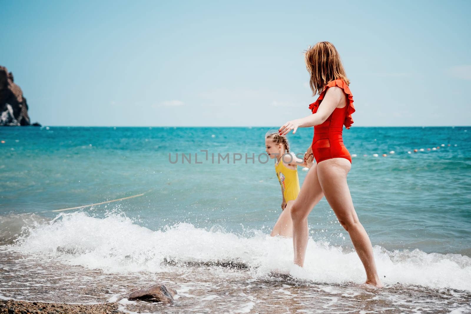 Happy loving family mother and daughter having fun together on the beach. Mum playing with her kid in holiday vacation next to the ocean - Family lifestyle and love concept.