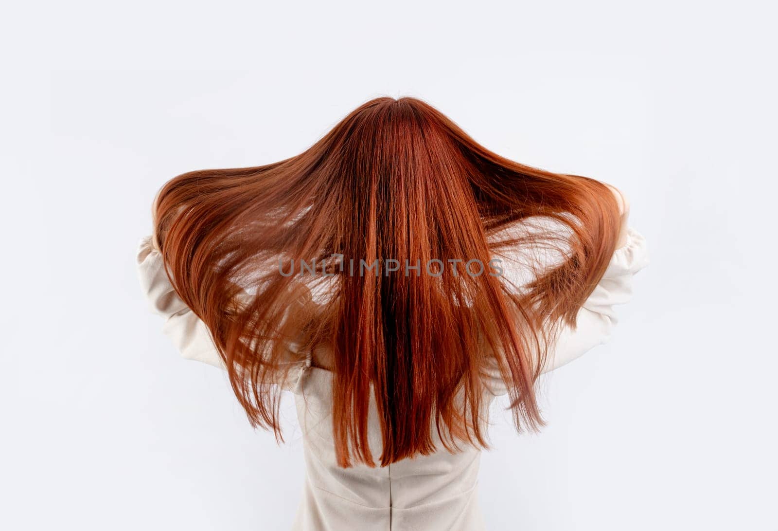back view of a young beautiful woman touching her red hair on white background, copy space by Desperada