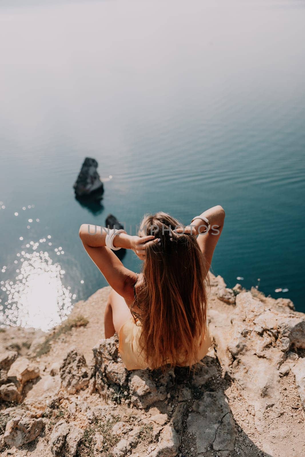 Woman travel sea. Happy tourist taking picture outdoors for memories. Woman traveler looks at the edge of the cliff on the sea bay of mountains, sharing travel adventure journey.