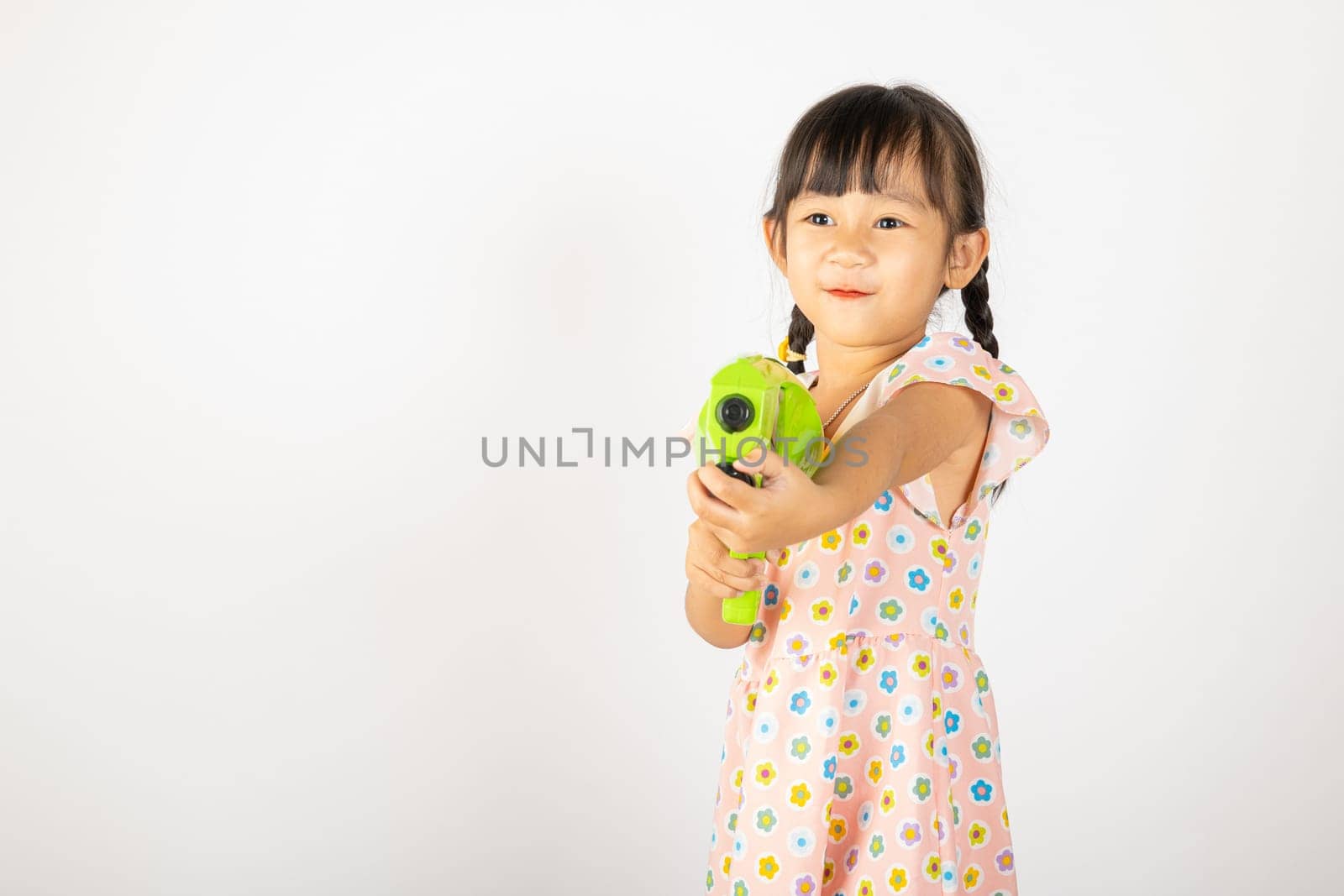 Happy Songkran Day, Asian little girl holding plastic water gun, Thai child funny hold toy water pistol and smile, isolated on white background, Thailand Songkran festival national culture concept