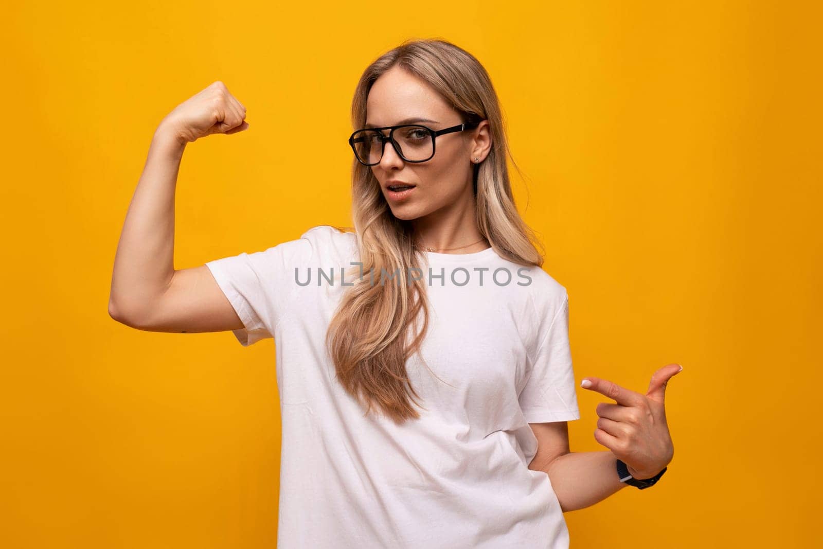 girl student in glasses and a white T-shirt on a studio yellow background.