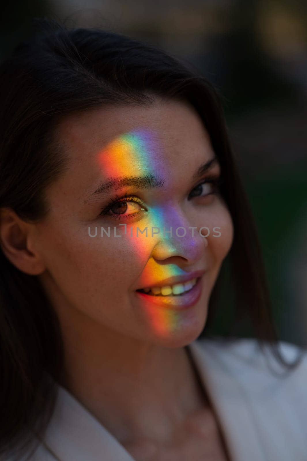 Portrait of caucasian woman with rainbow beam on her face outdoors. by mrwed54