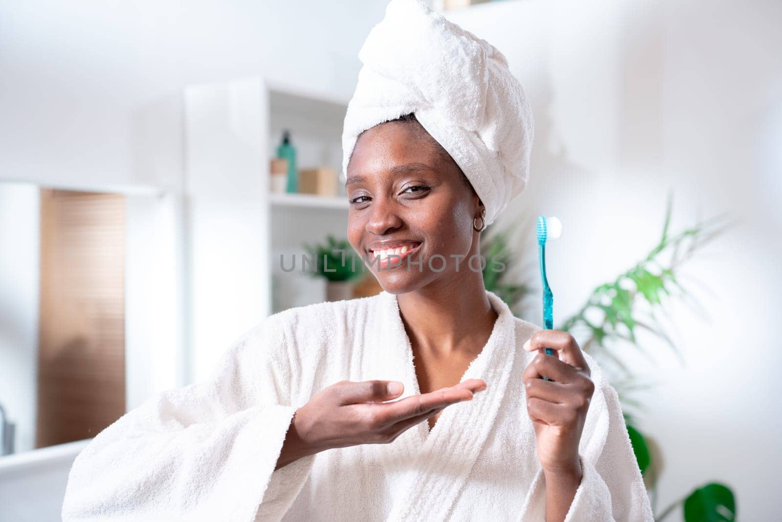 Positive young African American woman holds toothbrush. Perfect smile, cleans teeth. by PaulCarr