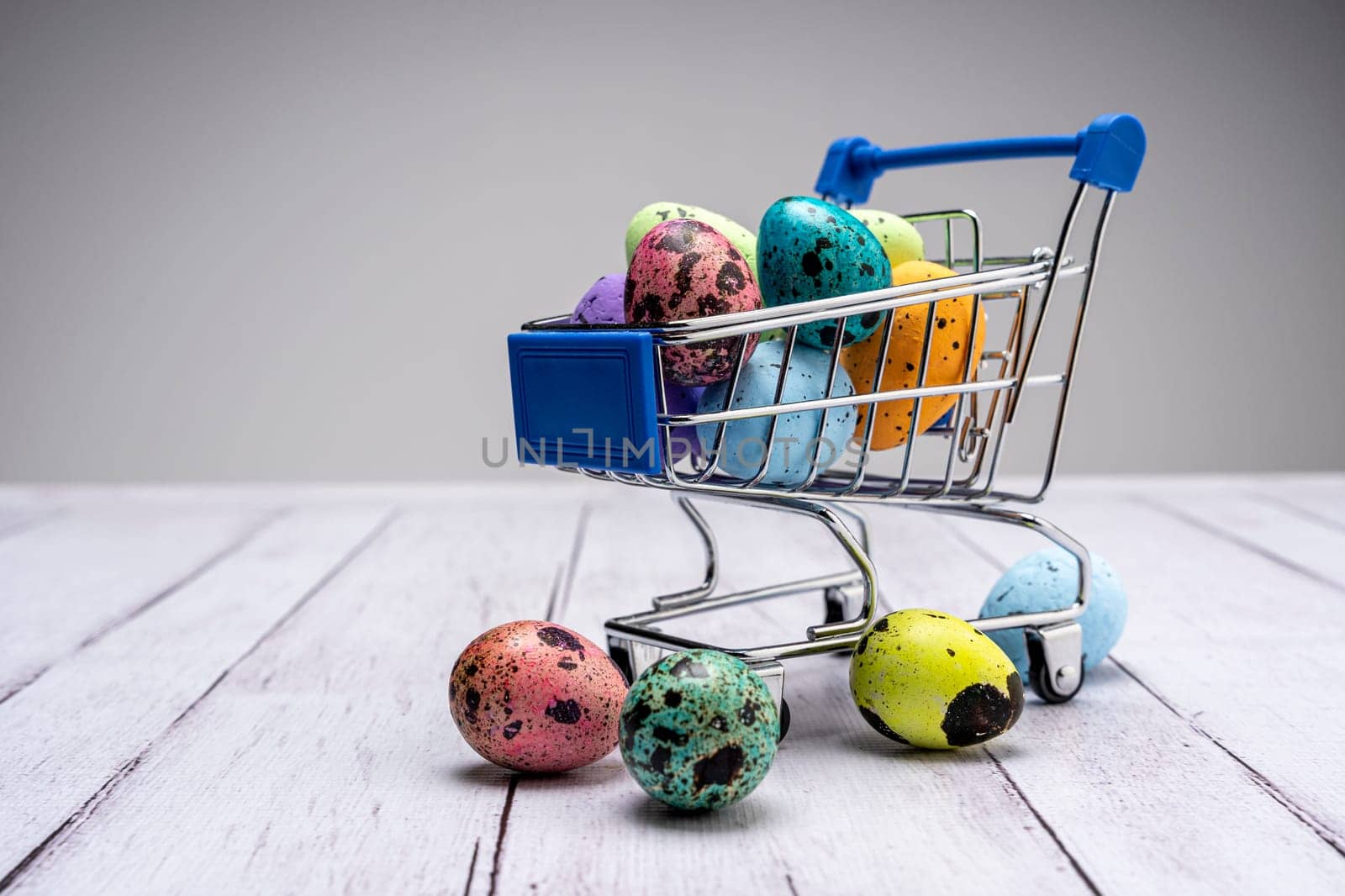 Colorful Easter eggs in a supermarket cart. Easter greeting card. Easter. Quail eggs. Spring holiday concept