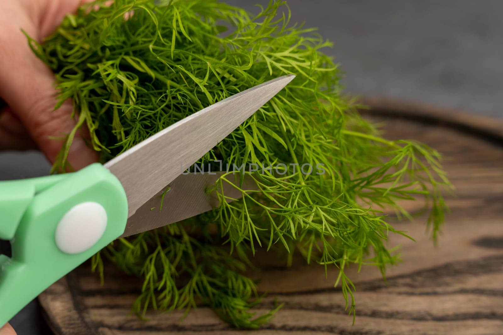 kitchen scissors cutting dill in the kitchen on a cutting board in the kitchen. Close-up of kitchen accessories. cooking. Fresh greens. Healthy eating. top side view
