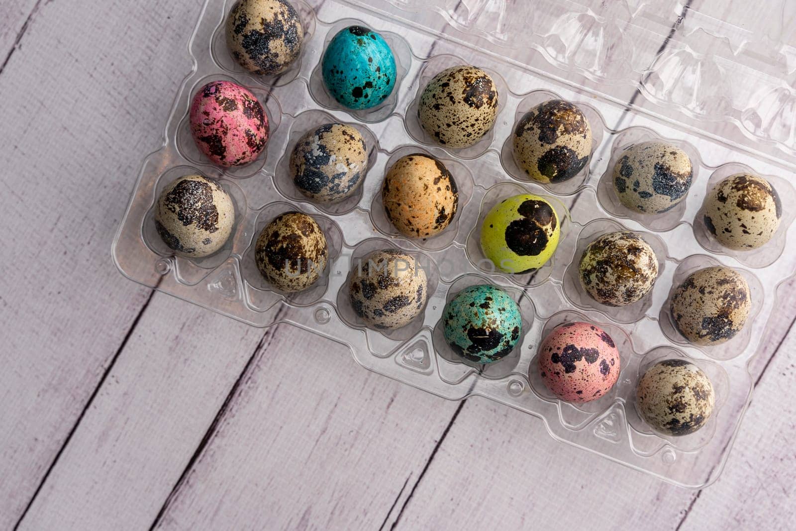 colorful Easter eggs in a container on a light background. Easter greeting card. a place to copy. close-up of quail eggs. top view