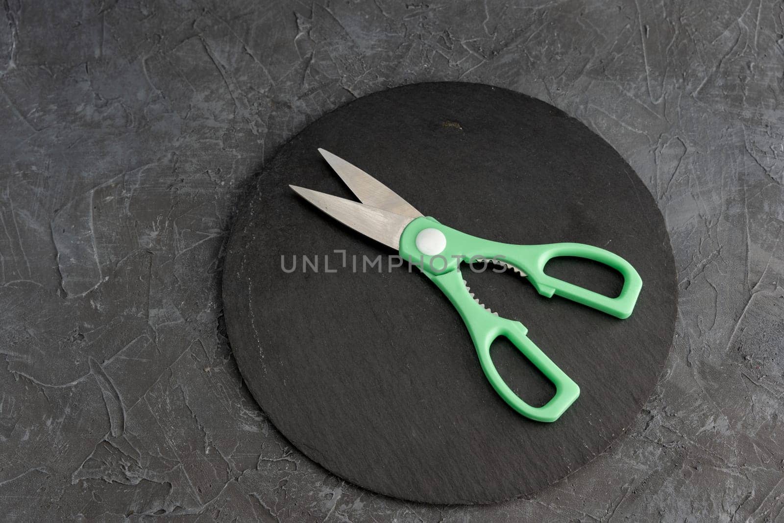 sharp kitchen scissors on a black slate cutting board in the kitchen. Close-up of kitchen accessories. cooking. Healthy eating. The cook's job.