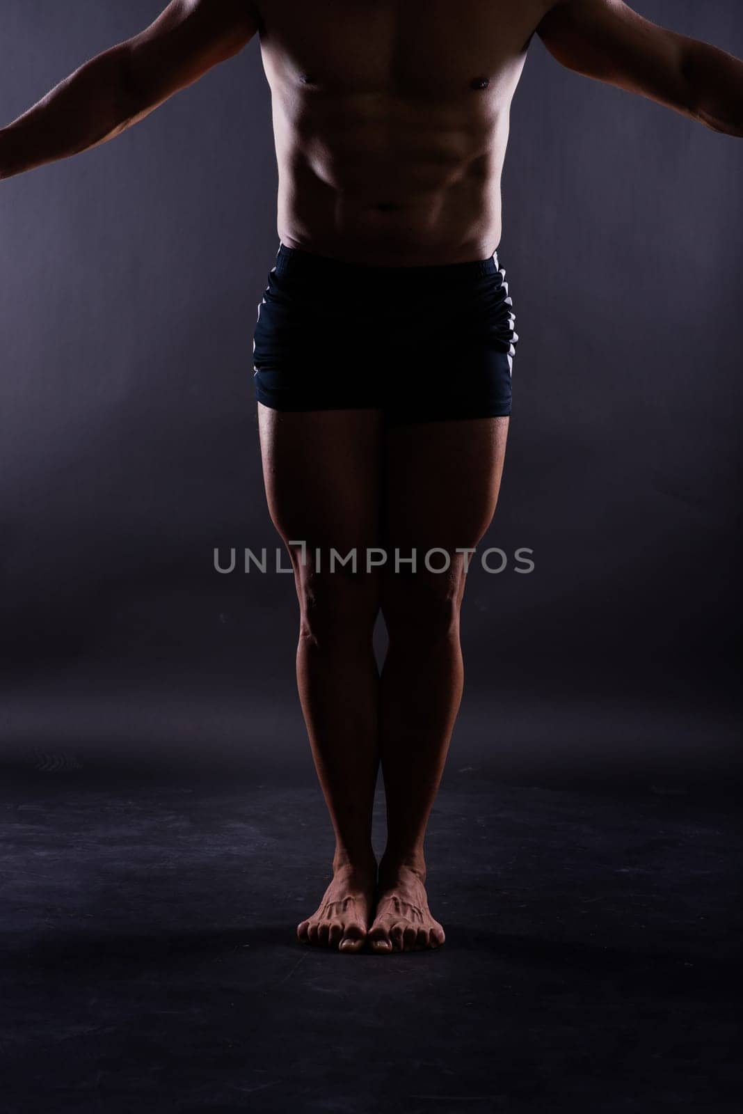 Muscular male legs close up studio shot dark background by Zelenin