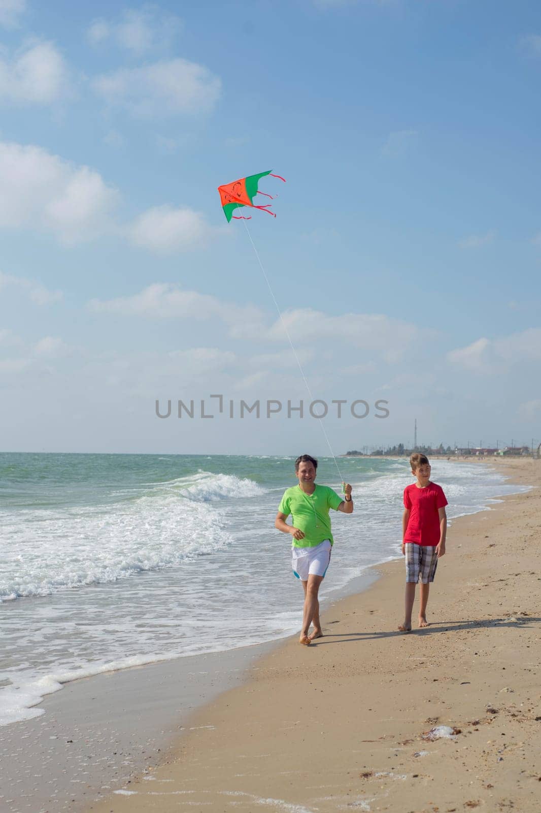 Rest of parents with children. Dad and son fly a kite near the sea