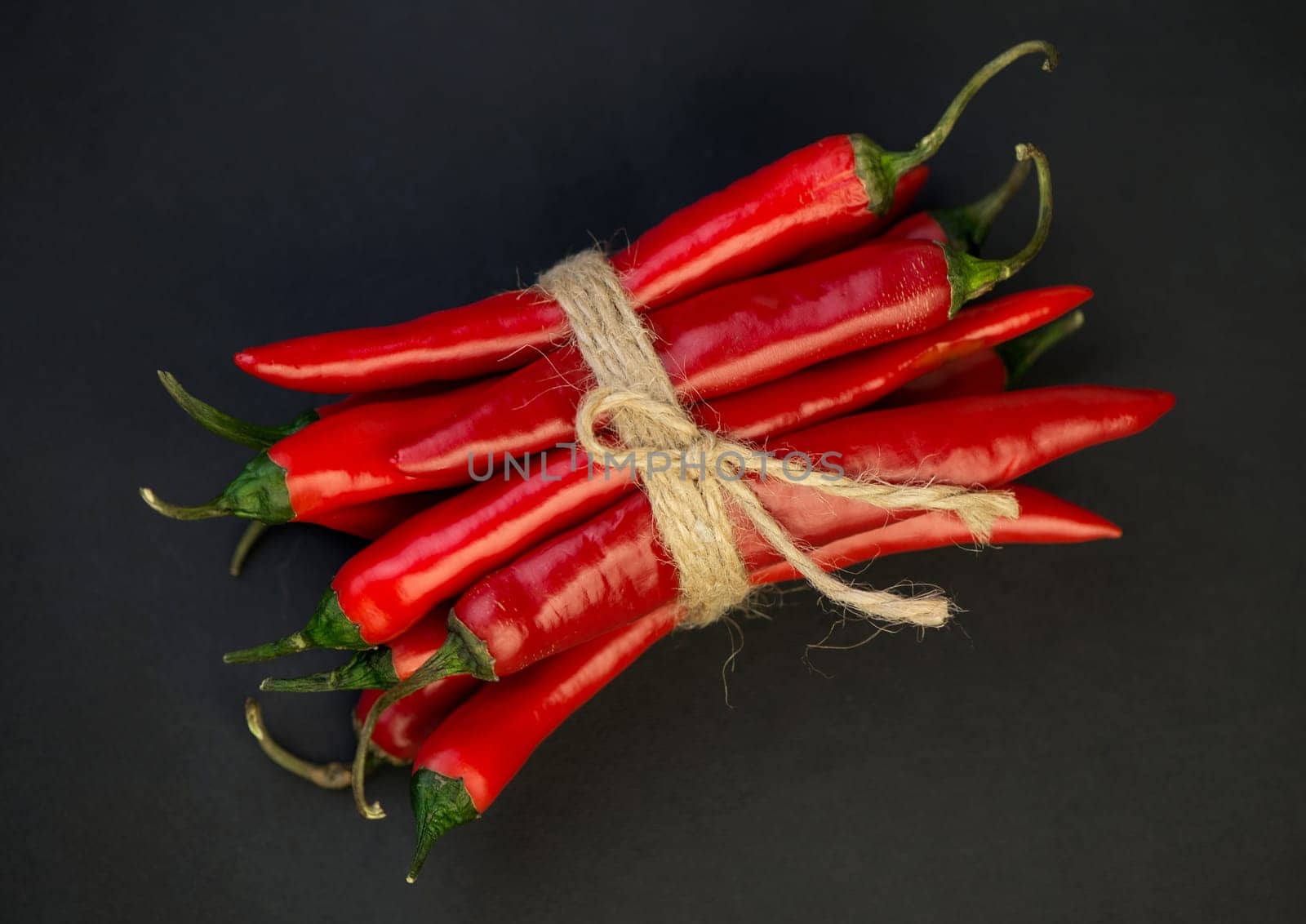 Chili pepper isolated on a black background. Knitted hot chili pepper tied with a rope. Chili hot pepper clipping path. by aprilphoto