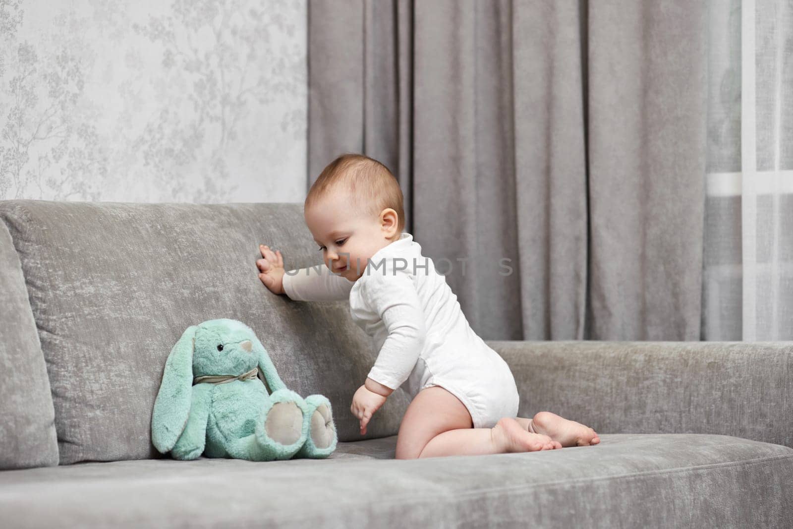 cute baby girl playing with soft toy bunny at home.