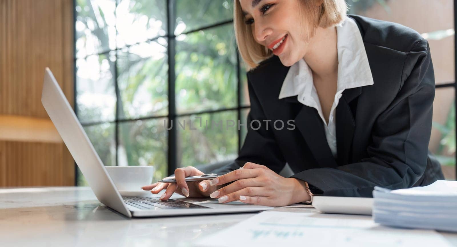 Portrait of young business woman using laptop and documents on the table at office by nateemee