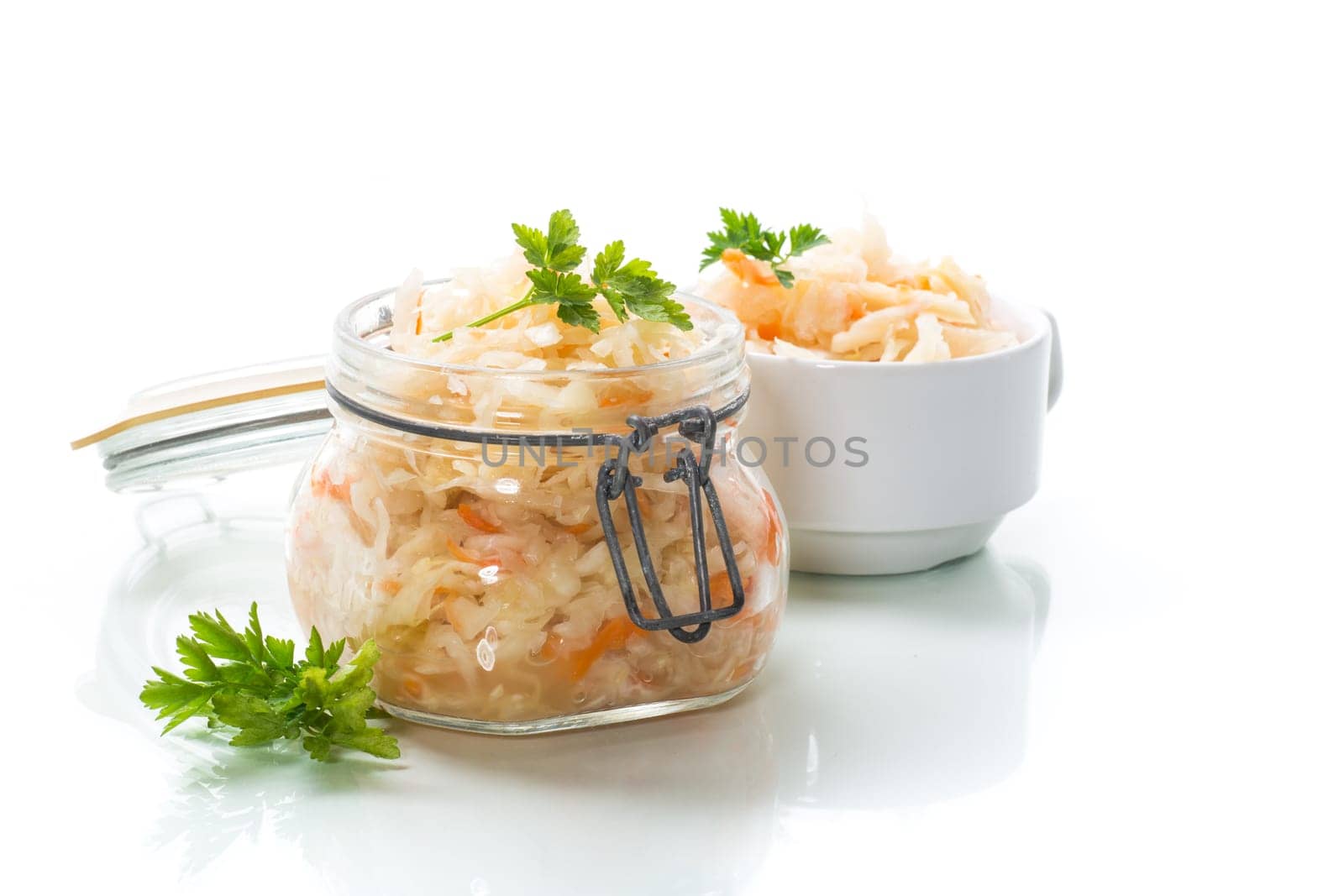 Sauerkraut with carrots and spices in a glass jar isolated on white background