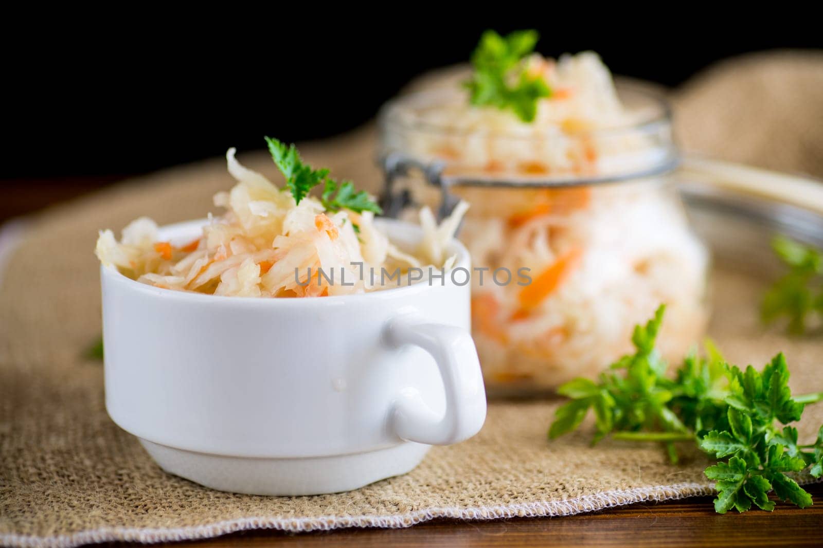 Sauerkraut with carrots and spices in a bowl on a wooden table.