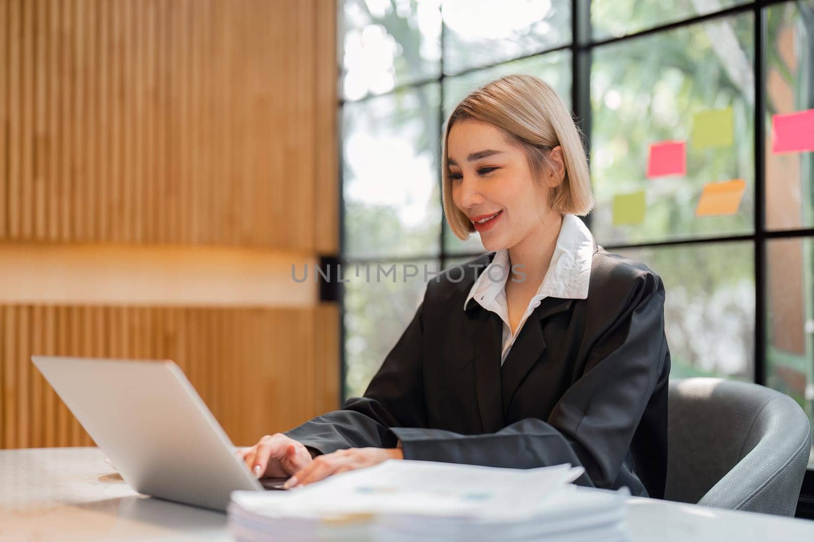 Portrait of young business woman using laptop and documents on the table at office.