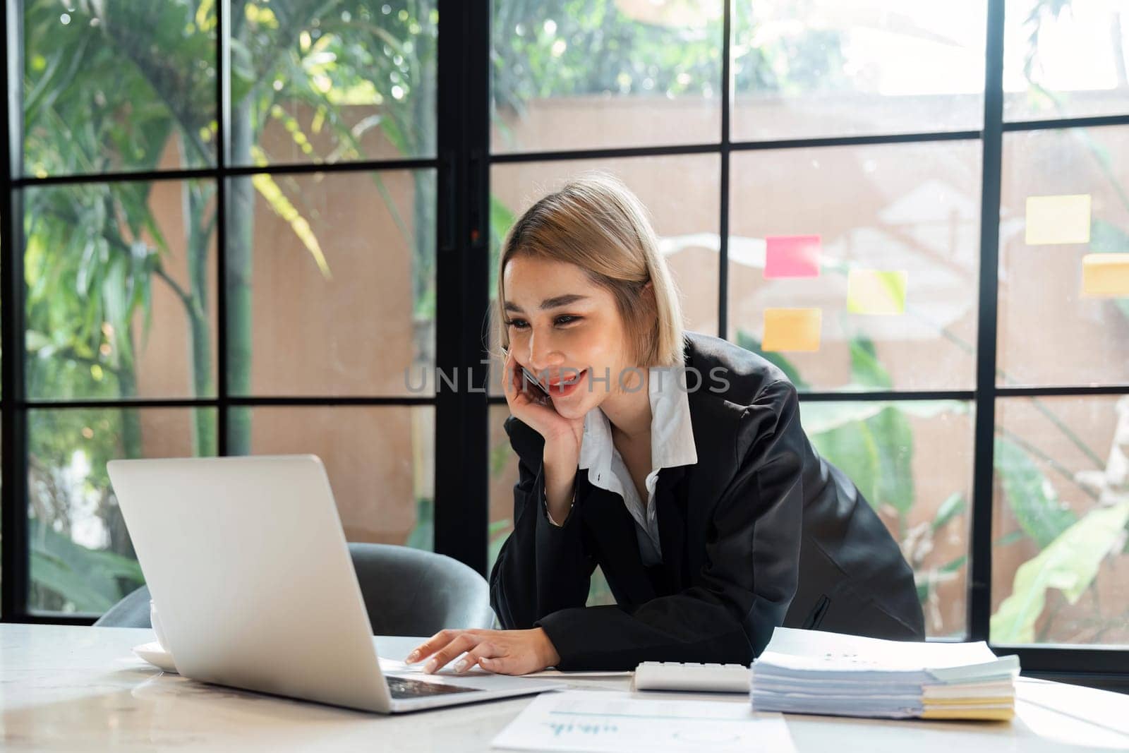 Portrait of young business woman using laptop and documents on the table at office.