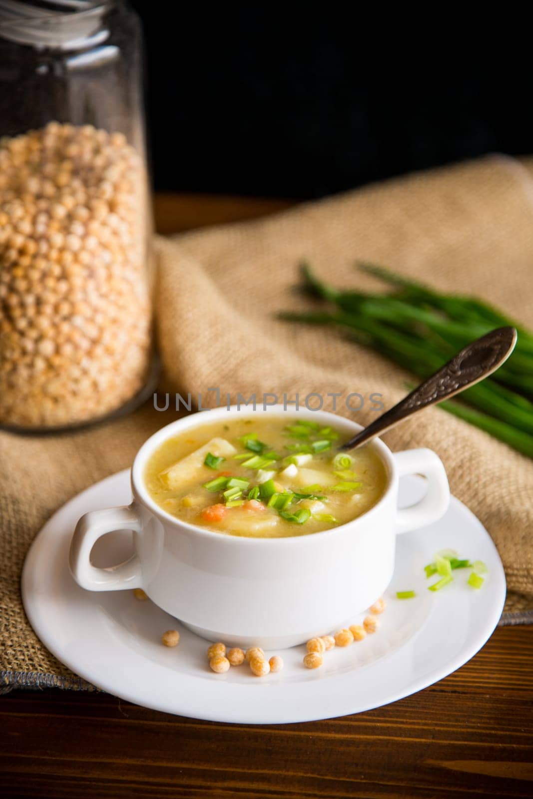 dried pea soup in a plate with herbs, on a wooden table.