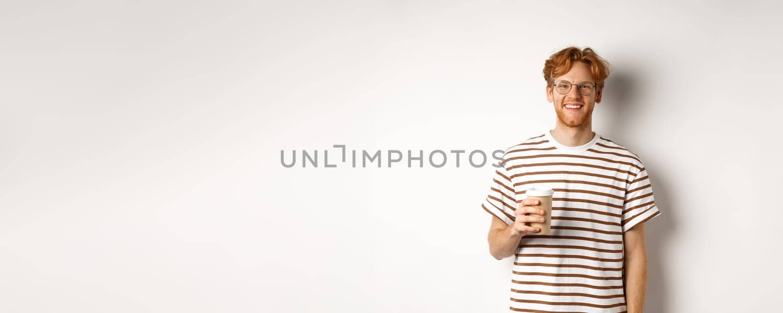 Handsome young man with beard and red messy hair, wearing glasses with striped t-shirt, drinking coffee from takeaway and smiling, white background by Benzoix