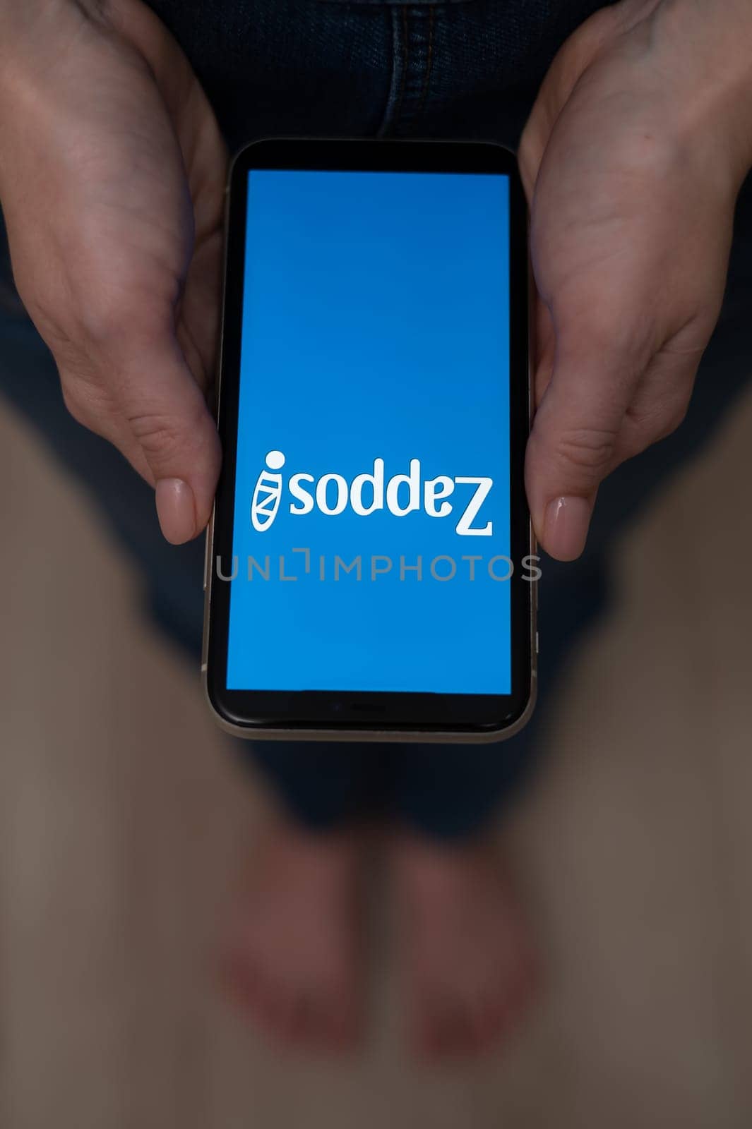 December 3, 2022 Almaty Kazakhstan: Barefoot woman holding smartphone with zappos logo