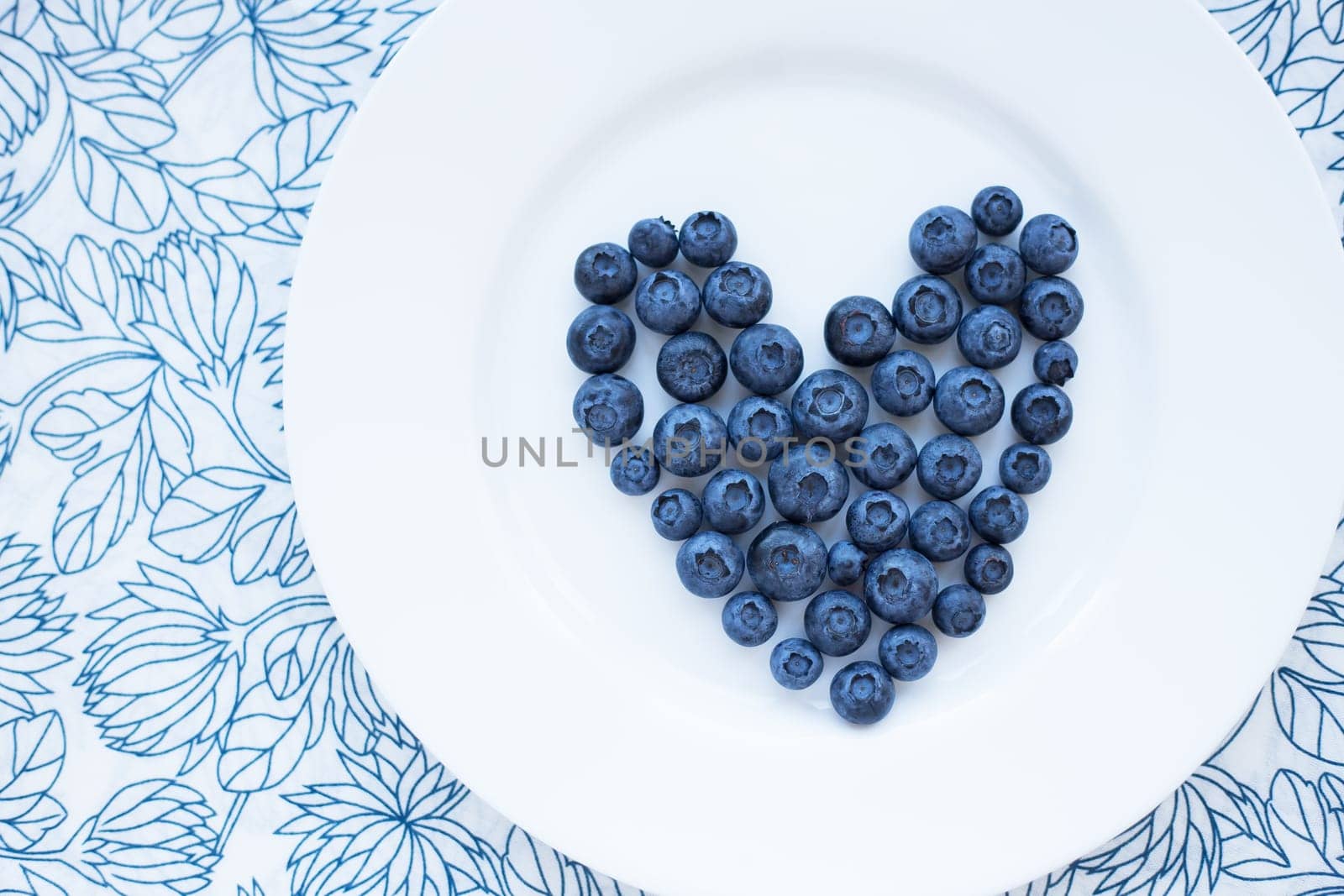 blueberries in a heart shape on a white plate. valentine card