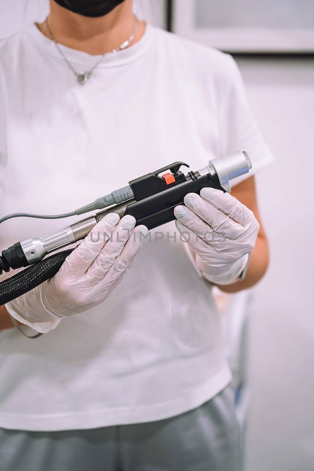 Close up shot of gloved hand with the laser hair removal machine's handpiece. Alexandrite laser techhnology removing hair. Beauty technology concept