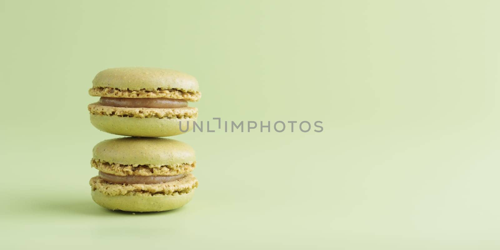 Green pistacio colored macaroons on green background. Gift for 8 March, International Women's Day, Valentine Day. Horizontal banner with copyspace