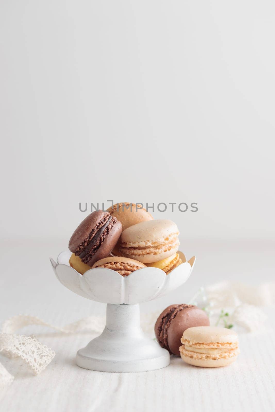 Chocolate, vanilla, coffee eco handmade natural macaroons in a vase on white table. Gift for 8 March, International Women's Day, Valentine Day. Vertical banner closeup with a copyspace