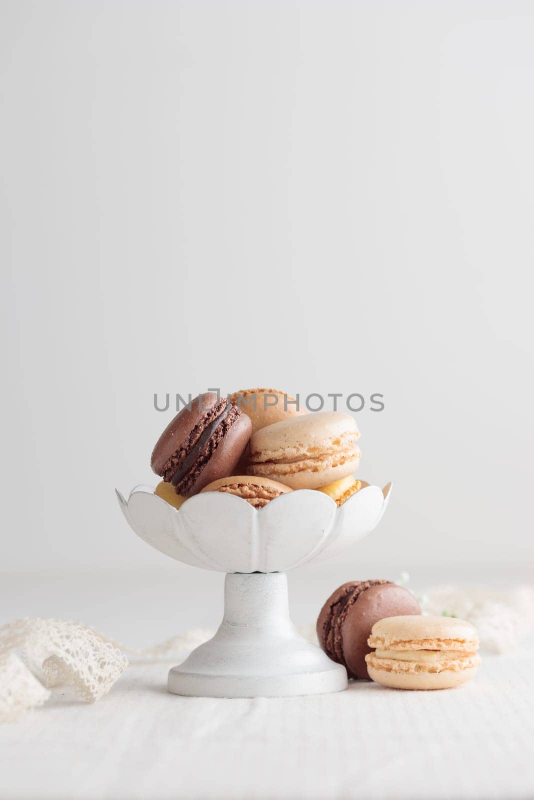 Chocolate, vanilla, coffee eco handmade natural macaroons in a vase on white table. Gift for 8 March, International Women's Day, Valentine Day. Vertical banner closeup with a copyspace
