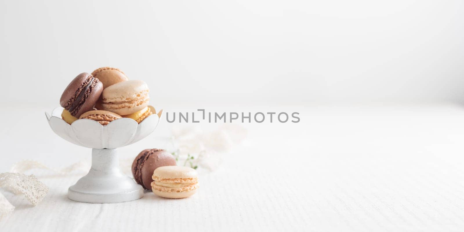 Chocolate, vanilla, coffee eco handmade natural macaroons in a vase on white table. Gift for 8 March, International Women's Day, Valentine Day. Horizontal banner closeup with a copyspace