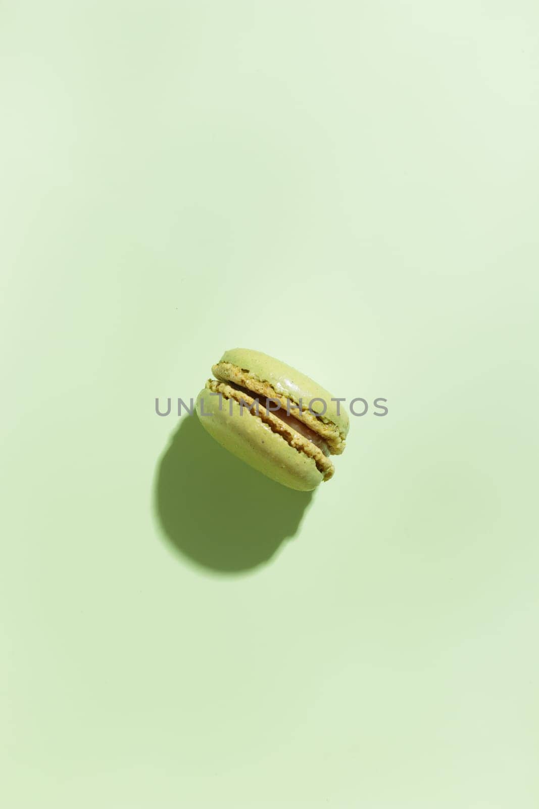 Green pistacio colored macaroon on green background. Gift for 8 March, International Women's Day, Valentine Day. Horizontal banner with copyspace