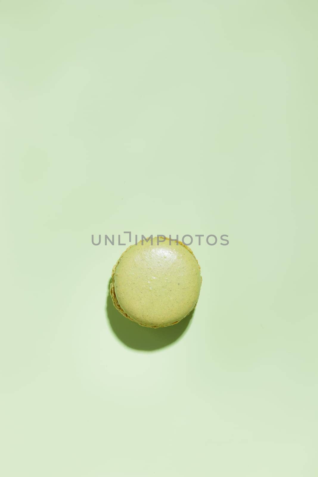 Green pistacio colored macaroon on green background. Gift for 8 March, International Women's Day, Valentine Day. Horizontal banner with copyspace