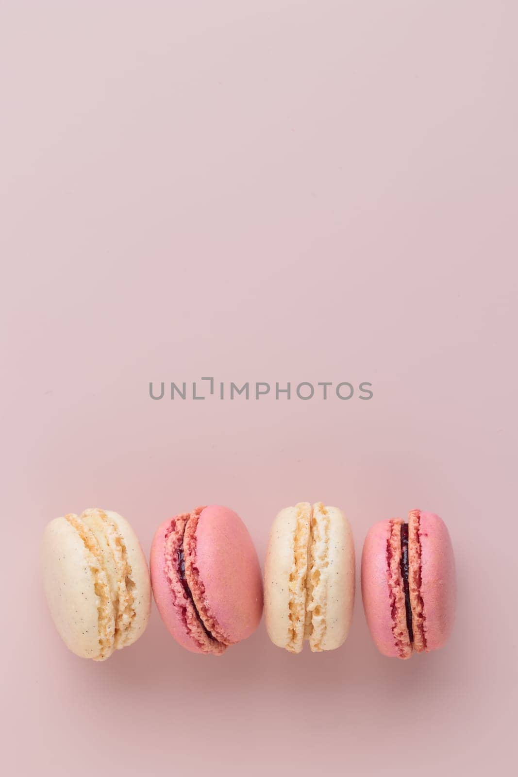 Macaroons on pink background, colorful french cookies pattern. Gift for 8 March, International Women's Day, Valentine Day. Vertical banner with copyspace