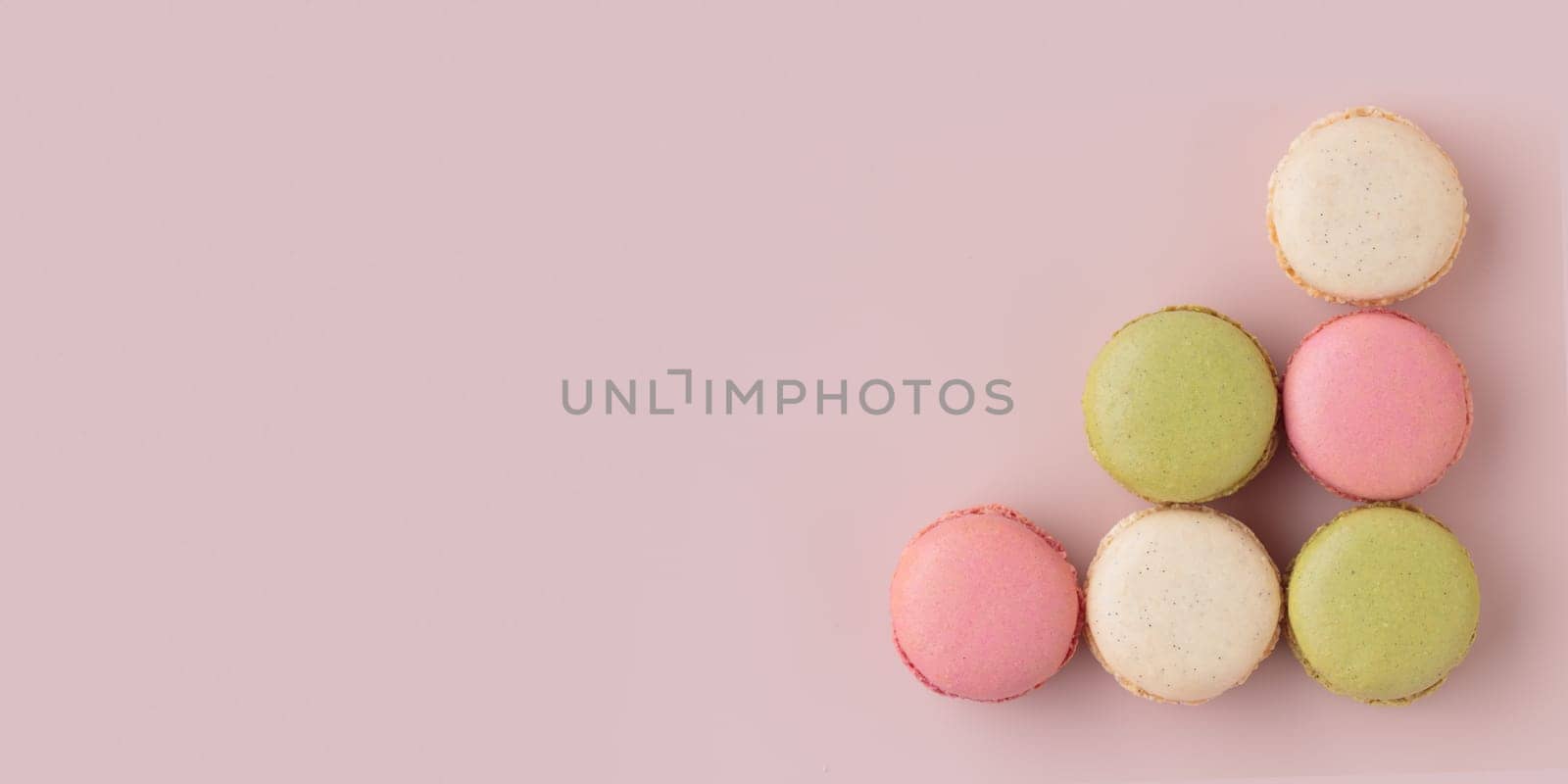 Colorful macaroons on pink background, top view, increase in profits of the confectionery production horizontal banner