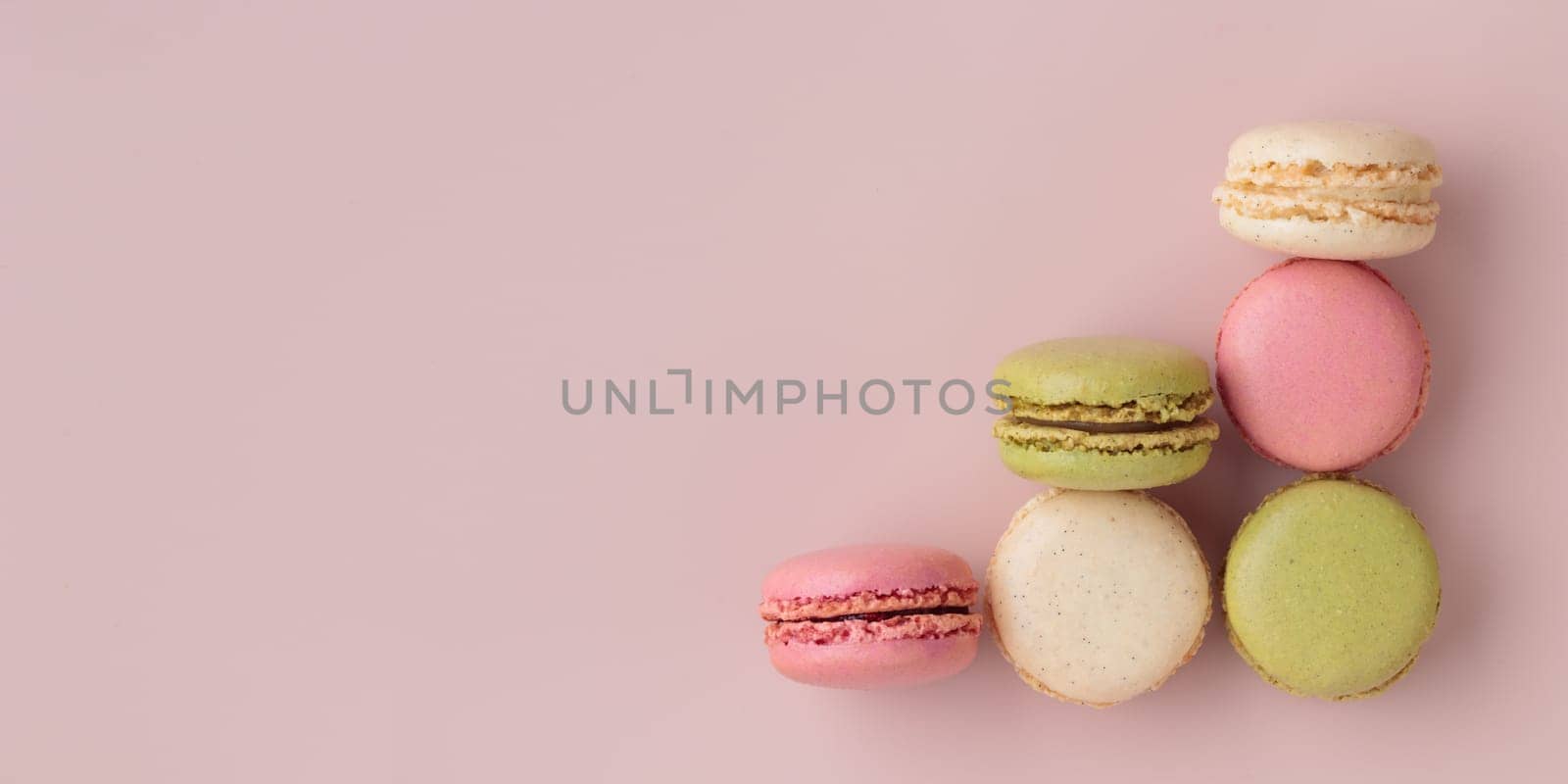 Colorful macaroons on pink background, top view, increase in profits of the confectionery production horizontal banner