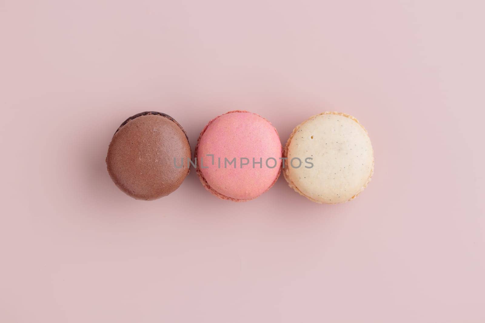 Three pastel colored macaroons on pink background, colorful french cookies pattern. Gift for 8 March, International Women's Day, Valentine Day. Horizontal banner with copyspace