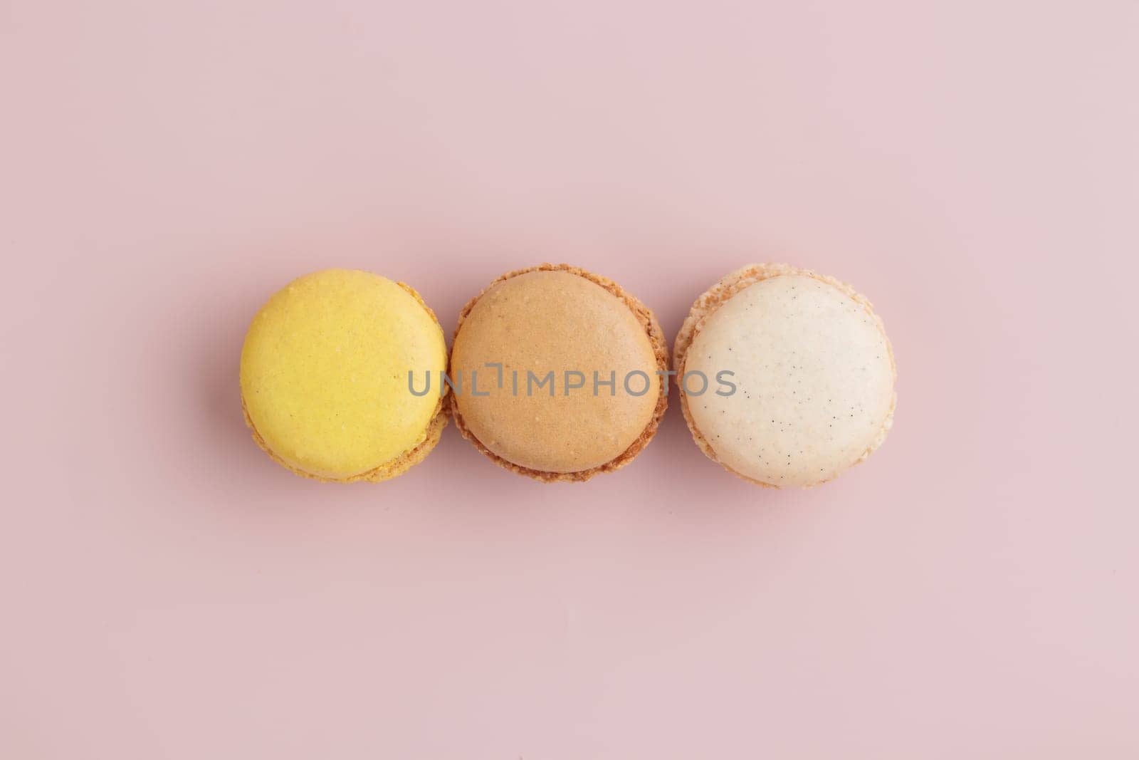 Three pastel colored macaroons on pink background, colorful french cookies pattern. Gift for 8 March, International Women's Day, Valentine Day. Horizontal banner with copyspace