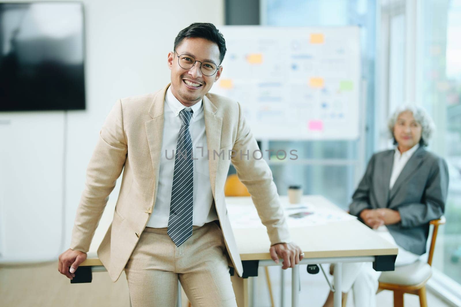 Portrait of a male business owner showing a happy smiling face as he has successfully invested his business using computers and financial budget documents at work by Manastrong