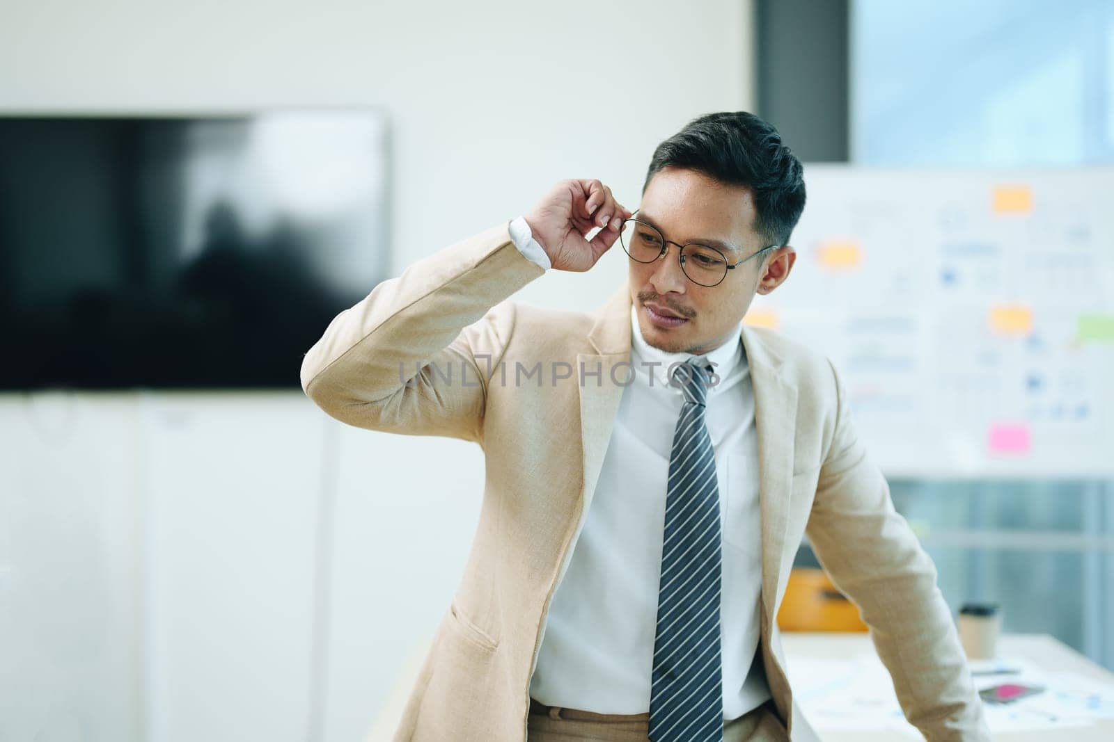 Portrait of a male business owner showing a happy smiling face as he has successfully invested his business using computers and financial budget documents at work.