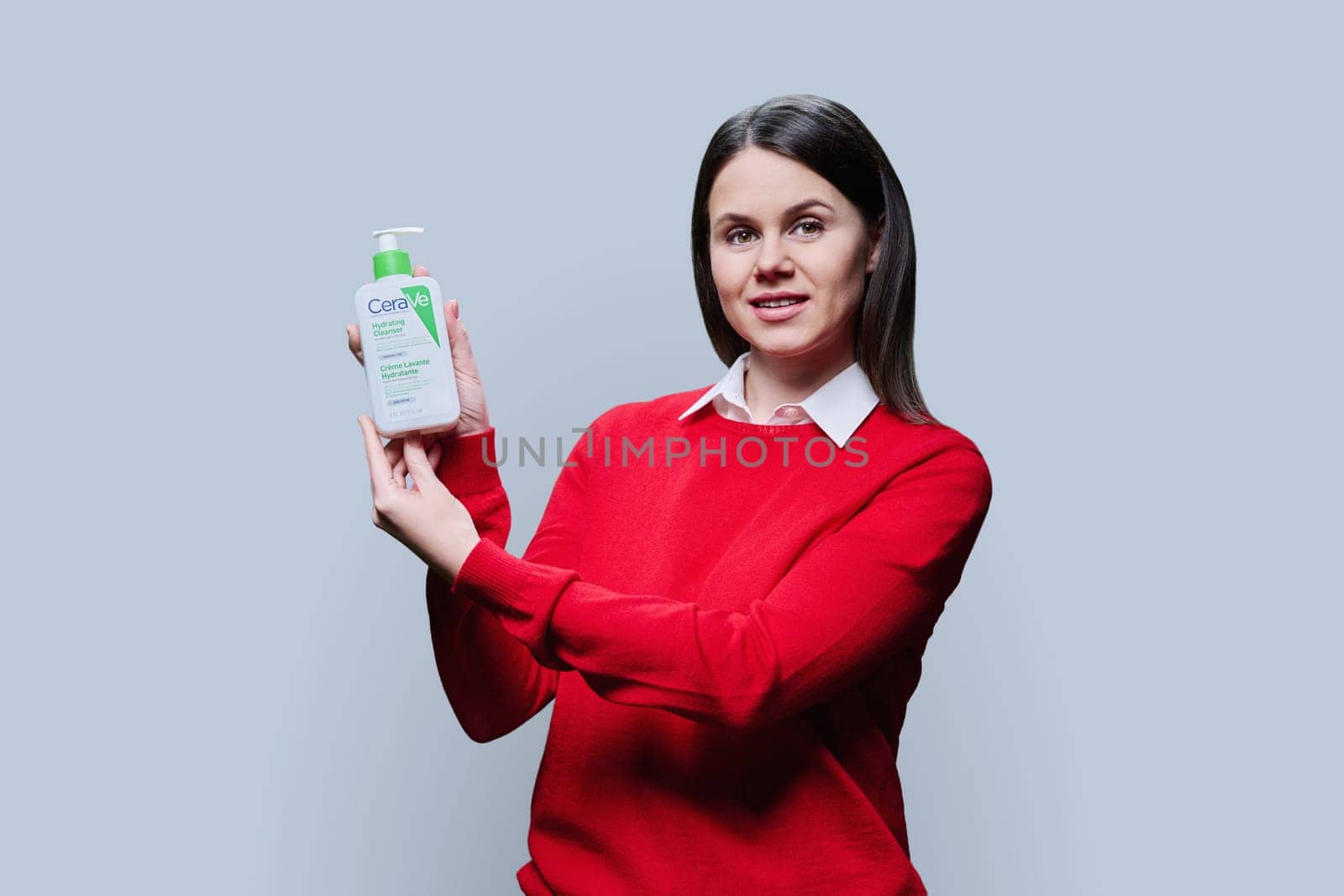 Kyiv, Ukraine, 01.03.2023, Pharmacy dermocosmetics, woman dermatologist recommending cleansing moisturizing emulsion CeraVe, hydrating cleanser for normal to dry skin, on light gray studio background