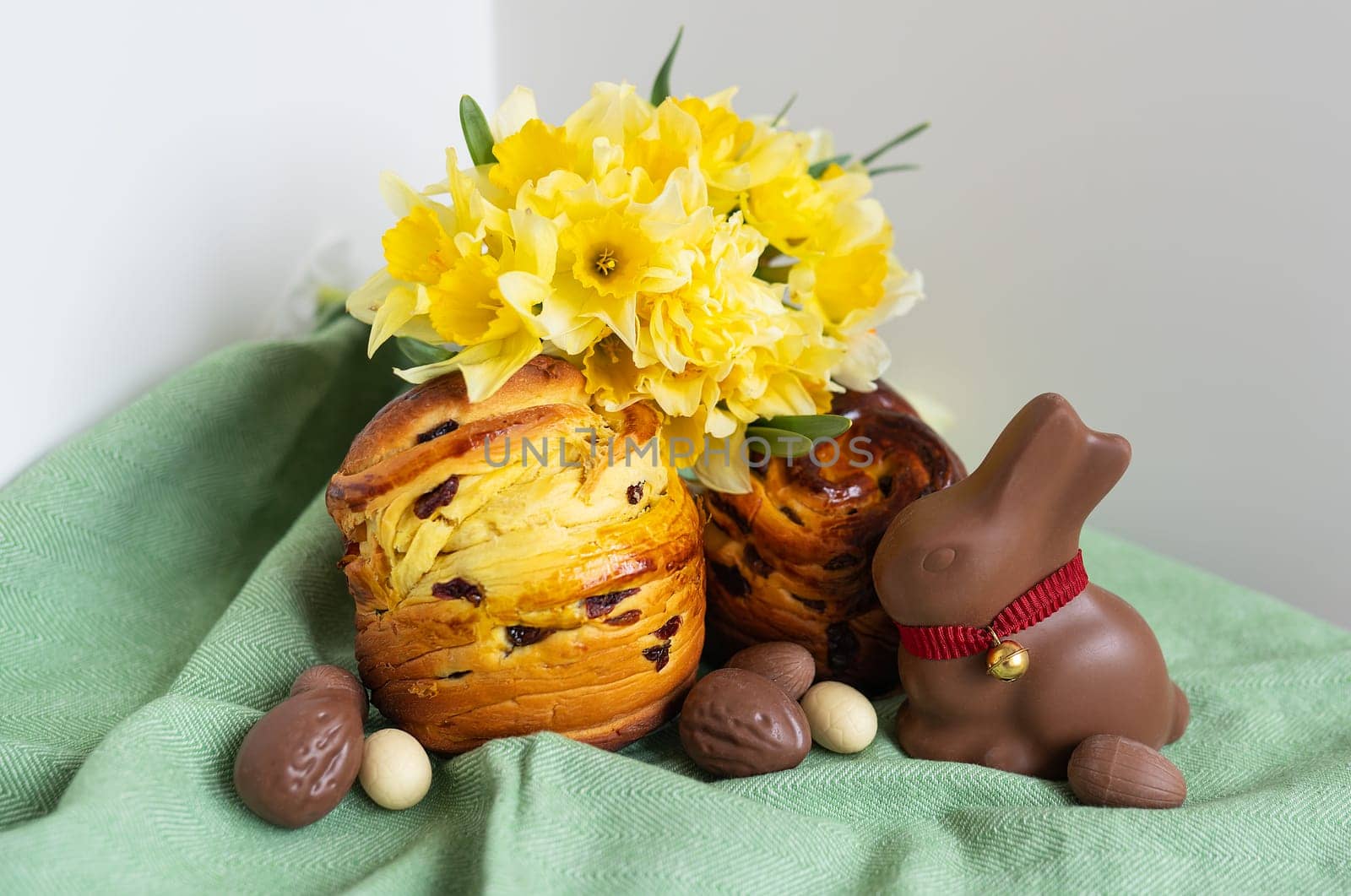 Homemade Easter traditional pastries lie on a green napkin along with daffodil flowers, rabbit, chocolate eggs. Easter baking and decoration. by sfinks