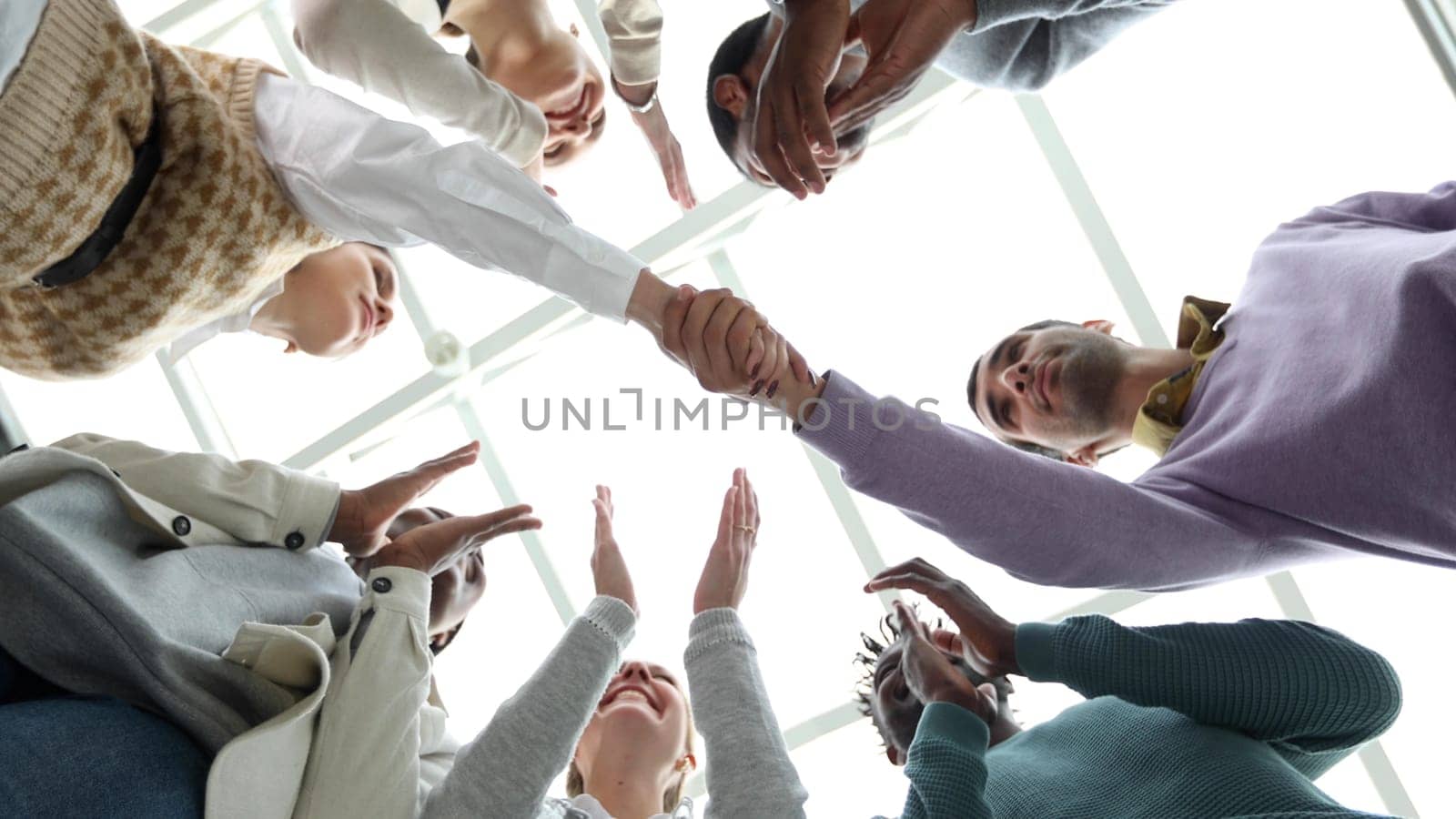 Closeup Business partners shaking hands, celebrating business success in modern office with high ceiling. Bottom View