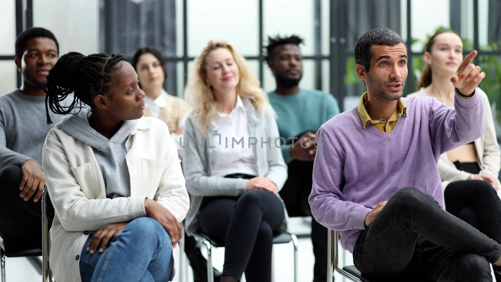 Close-up of people chatting, sitting in a circle and gesturing in a conference room