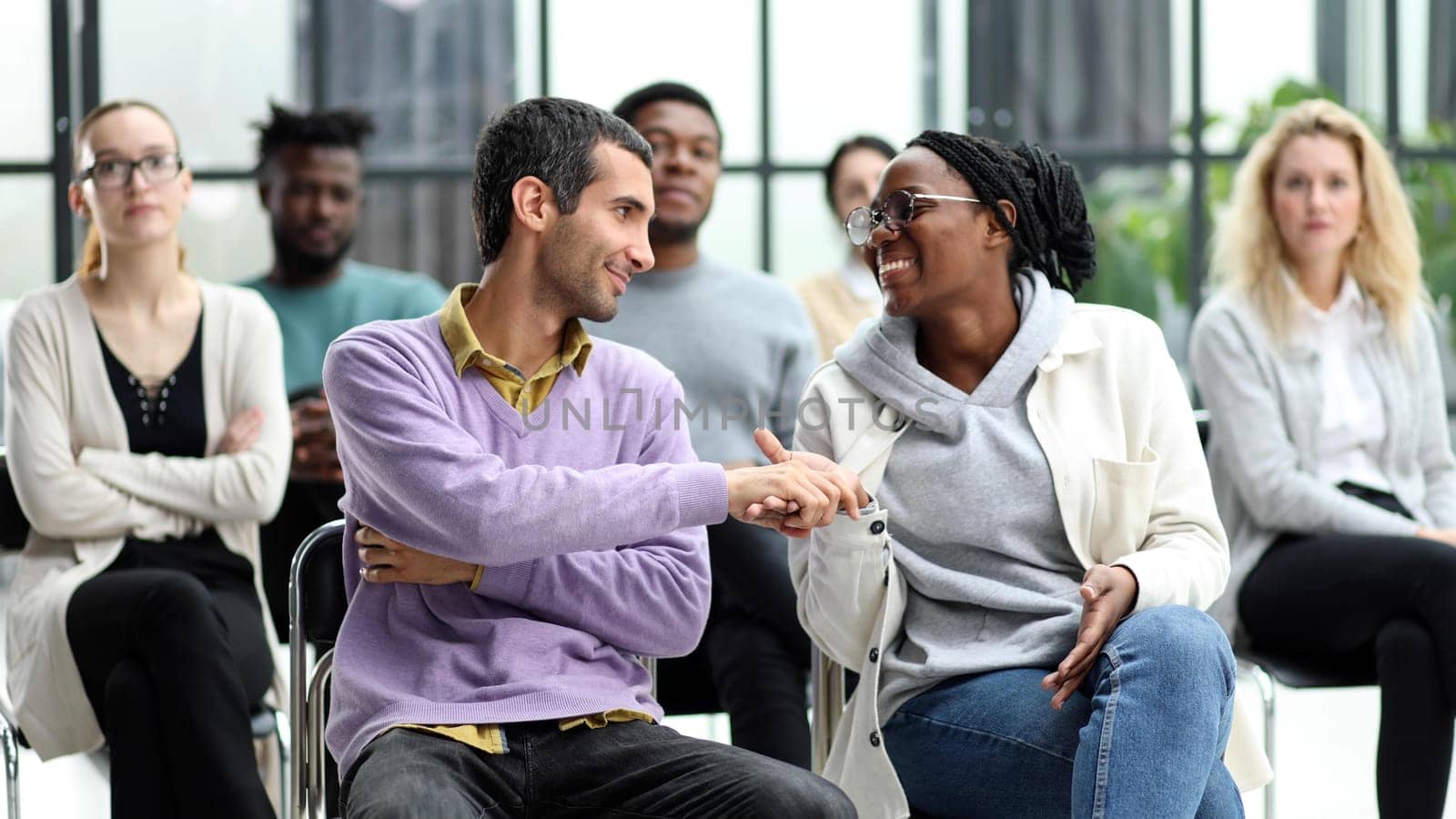 Selective focus of young businesswoman applauding together with interracial colleagues during seminar