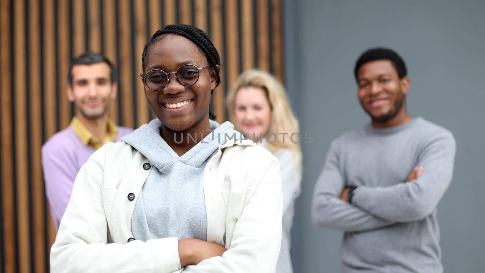 Young handsome editor is looking at the camera, acolytes are standing behind her