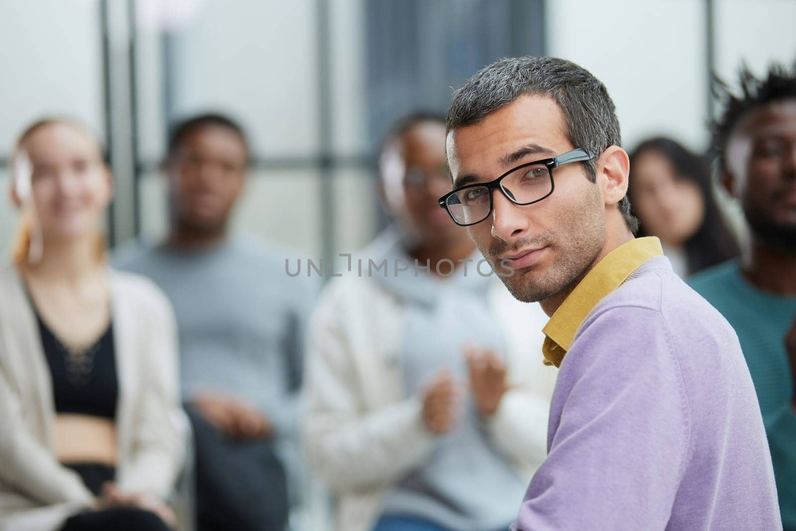 Portrait of a successful young professional businessman sitting over desk in front of colleague