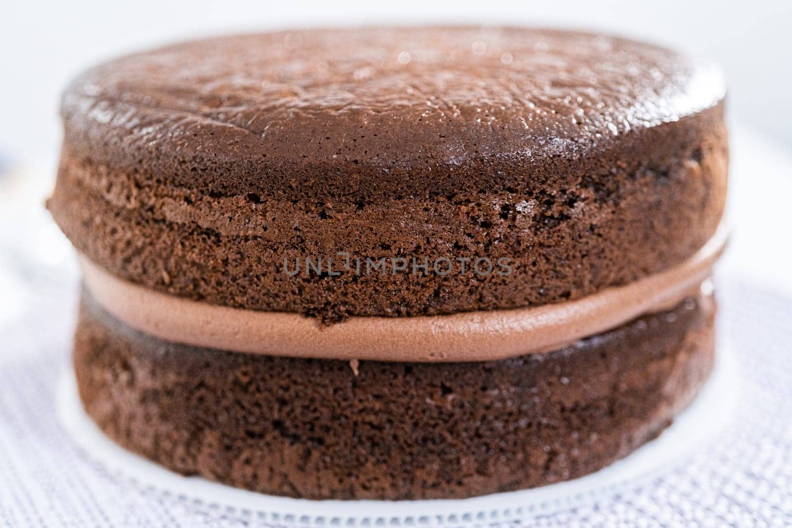 Covering chocolate cake with a crumb layer of chocolate buttercream frosting.